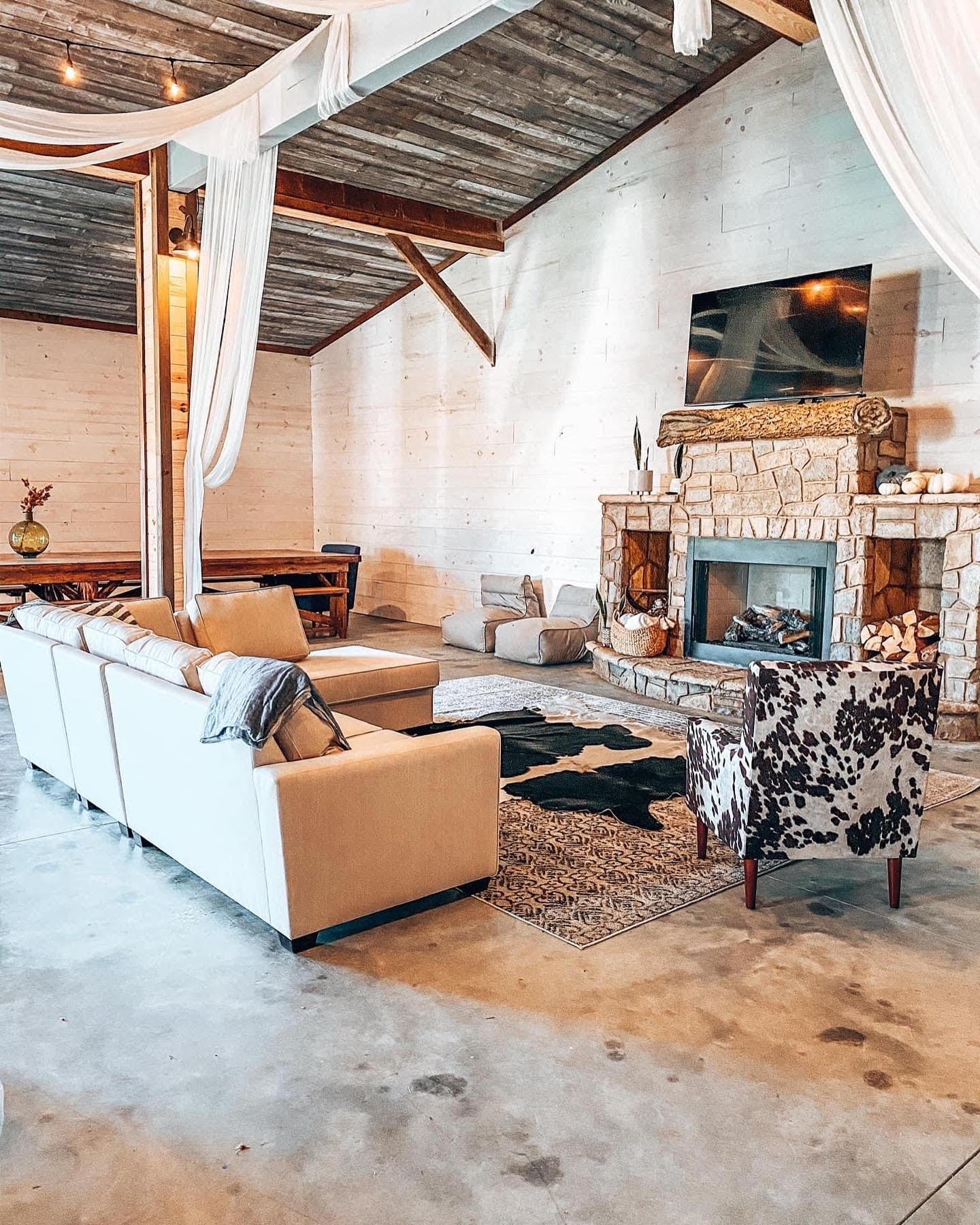 Living room with large wood beam and a fireplace with stone fireplace facade