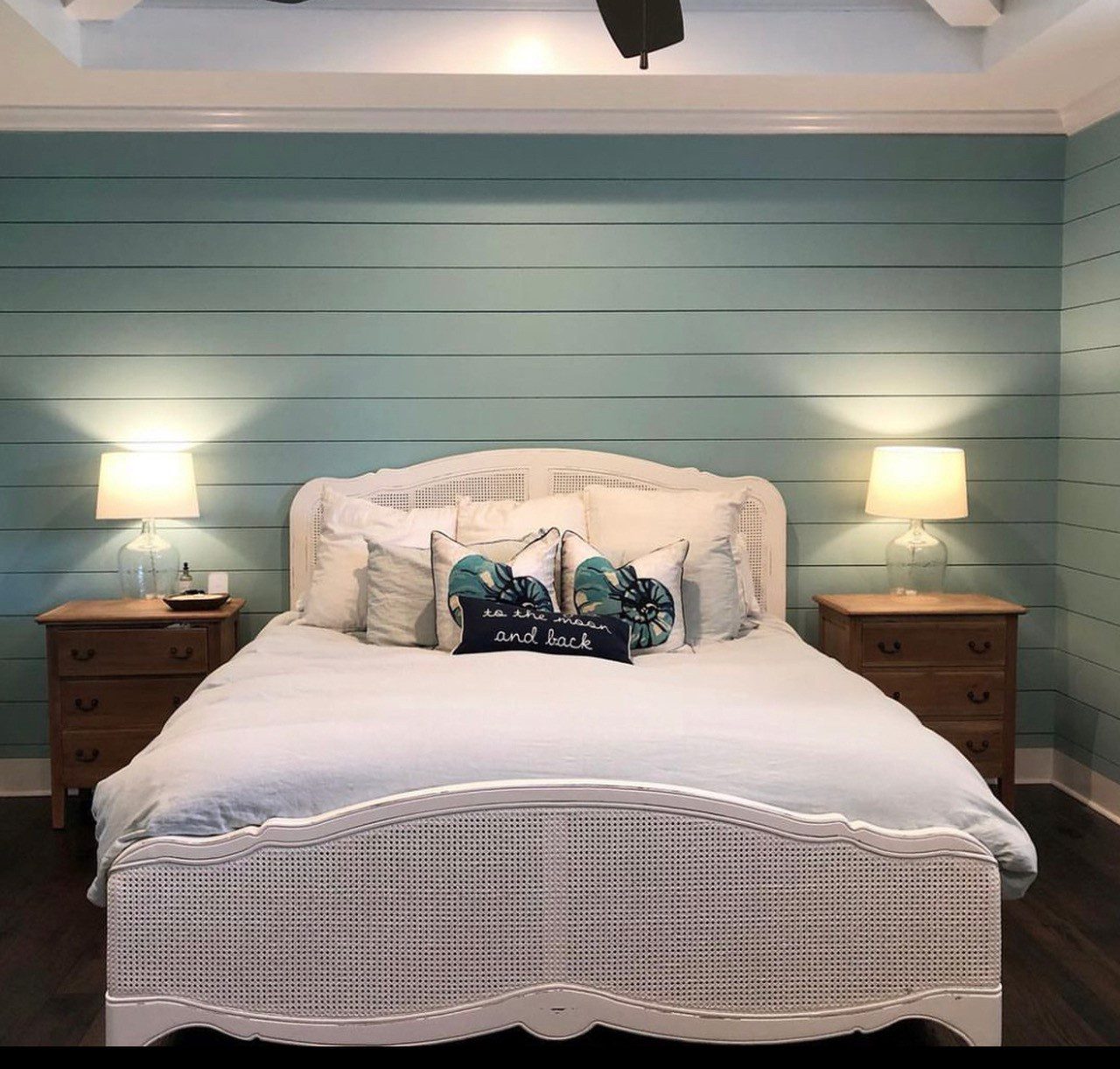 Bedroom with queen bed, two side tables with lamps and a blue shiplap wall