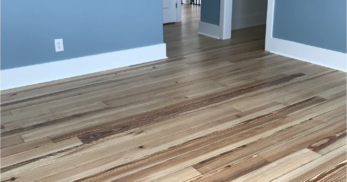 Empty room with hardwood flooring, blue walls, and white trim, leading to an open doorway.