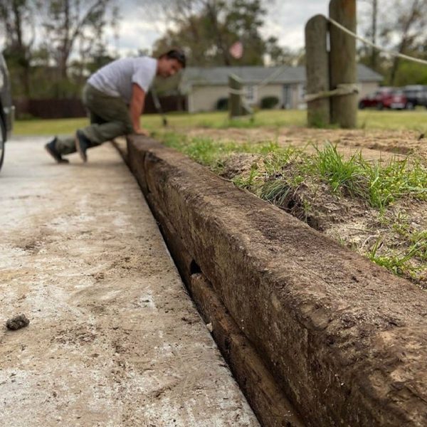 Man installing railroad ties as a retention wall